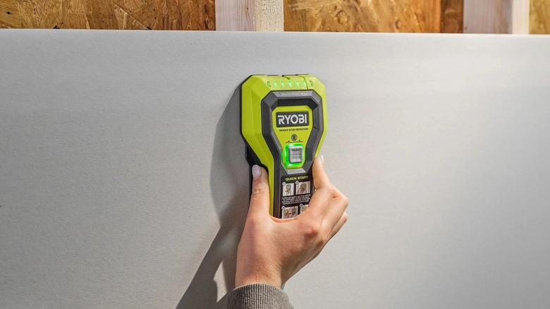 A Woman Using The Ryobi Whole Stud Detector On A Wall